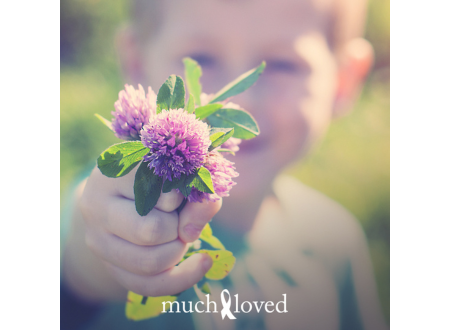Child holding out a bunch of purple flowers