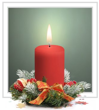 Red church candle surrounded by small green wreatth and red and gold ribbon 